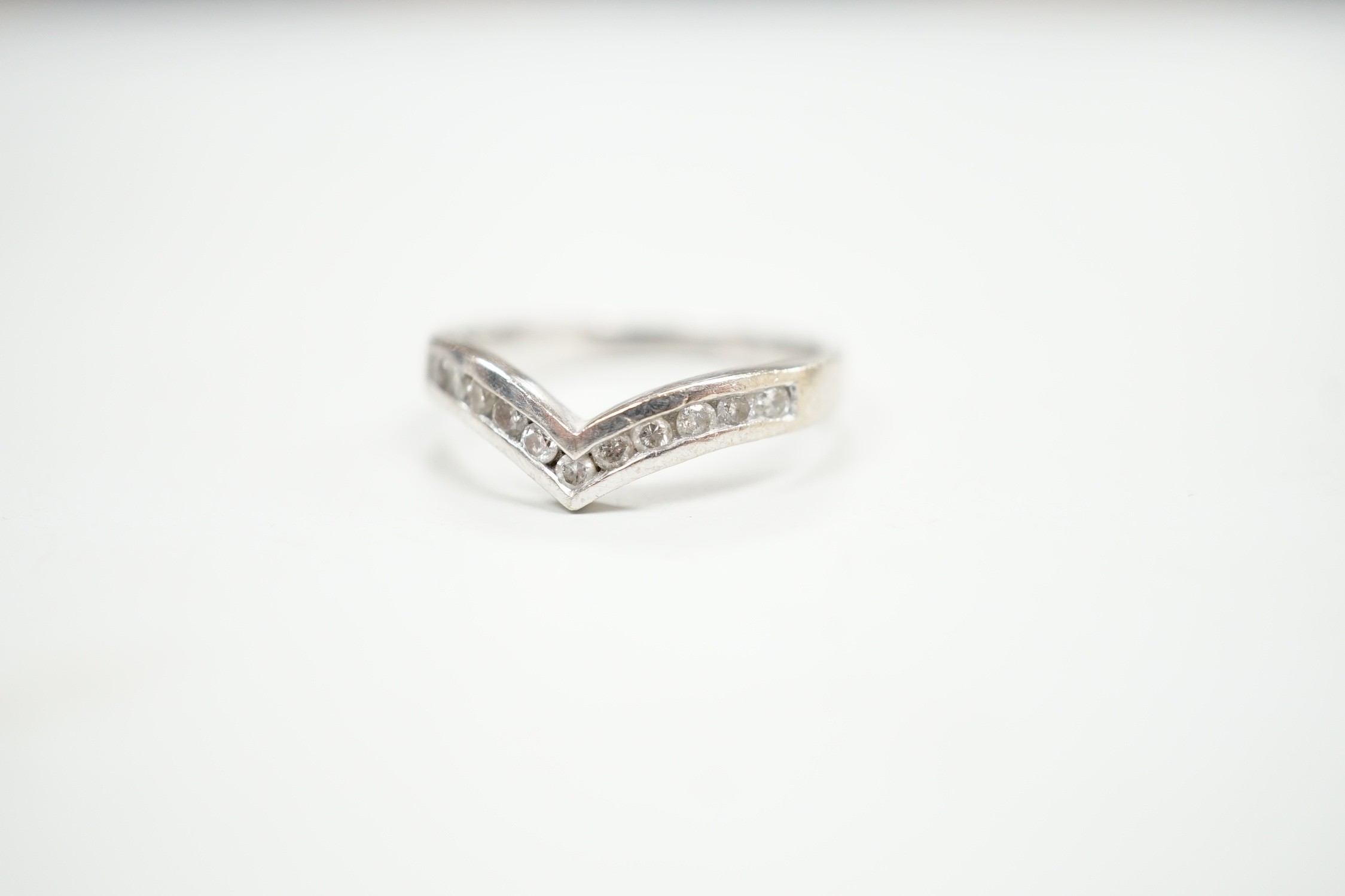 A modern 18ct white gold and channel set diamond chip wishbone shaped ring, size M, gross 3.4 grams.